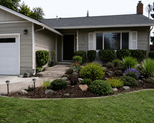 Well-maintained residential home with professionally landscaped garden beds, shrubs, mulch, and healthy front yard in Oakland, California.